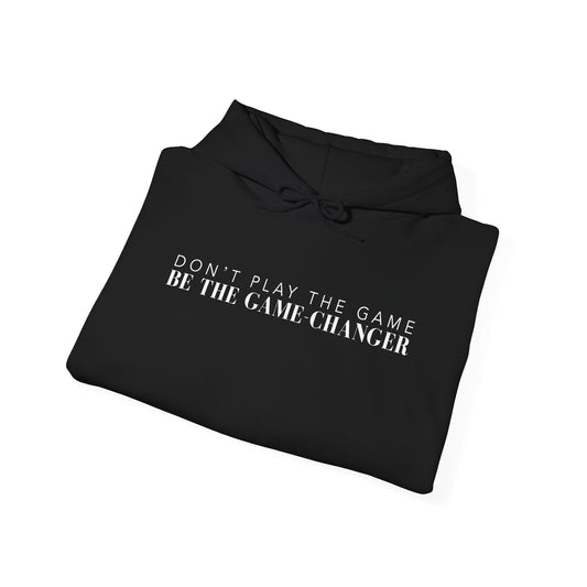A folded black hoodie with draw strings and white letters that say don't play the game be the game-changer across the chest