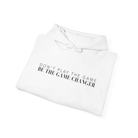 A folded white hoodie with draw strings and black letters that say don't play the game be the game-changer across the chest