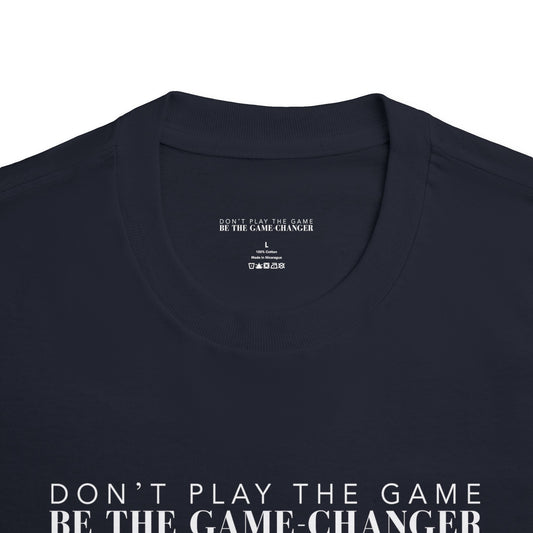 A close up of a short sleeve black t-shirt with white letters that say don't play the game be the game-changer that displays the inner label of the shirt with the brand name, size, where the shirt is made, what it is made of, and the laundry instructions