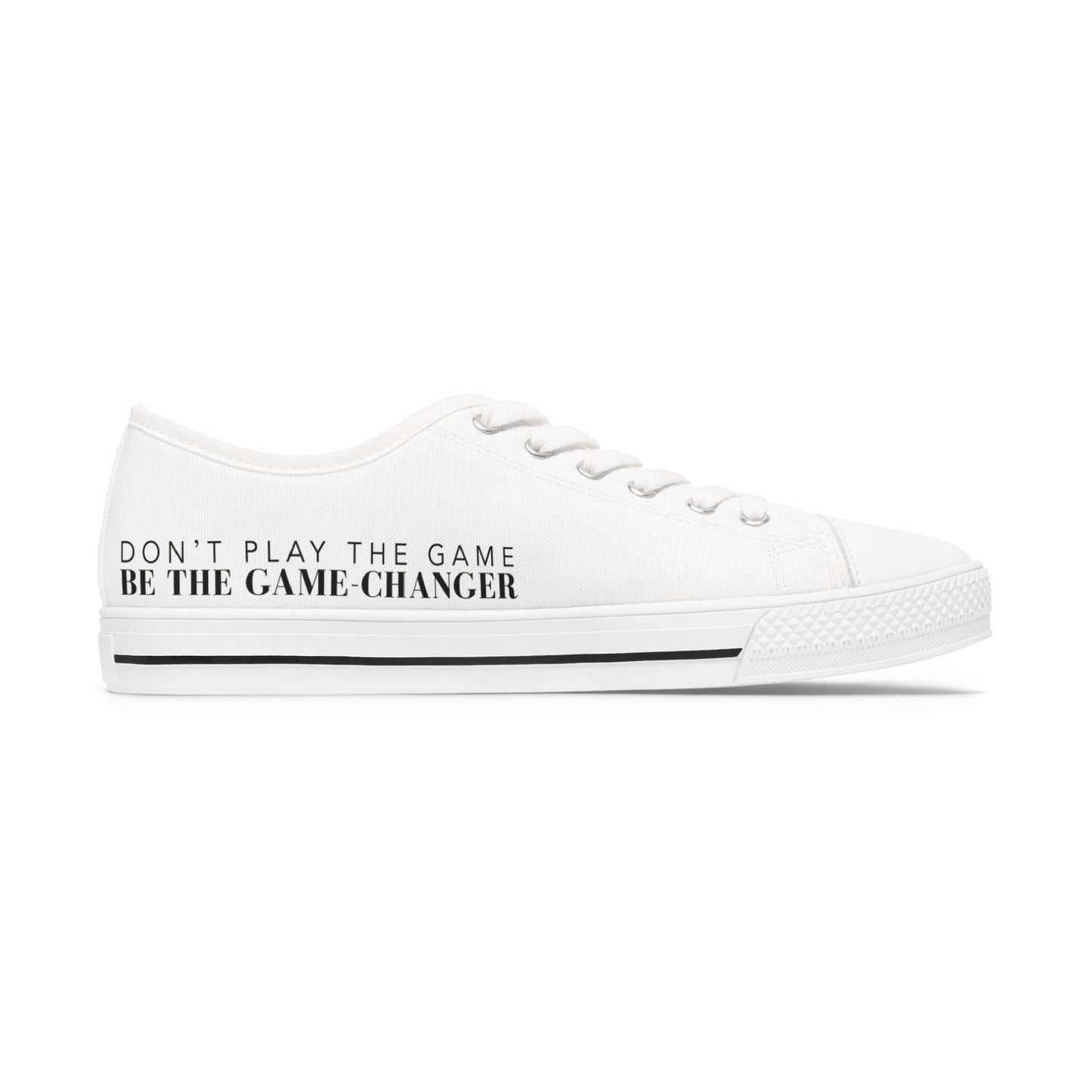 A side view of an all white women's converse style low top sneaker with don't play the game be the game changer written in black text across the side of the shoe with a black accent line in the leather trim