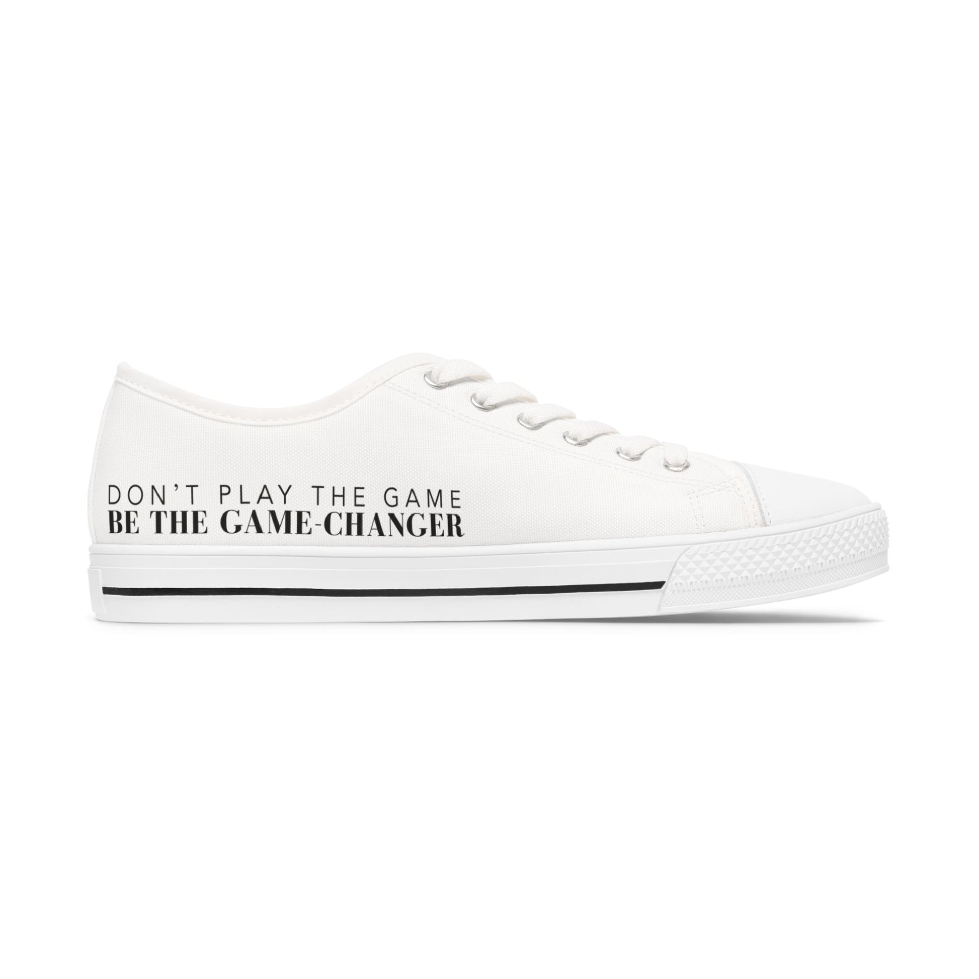 A side view of an all white women's converse style low top sneaker with don't play the game be the game changer written in black text across the side of the shoe with a black accent line in the leather trim
