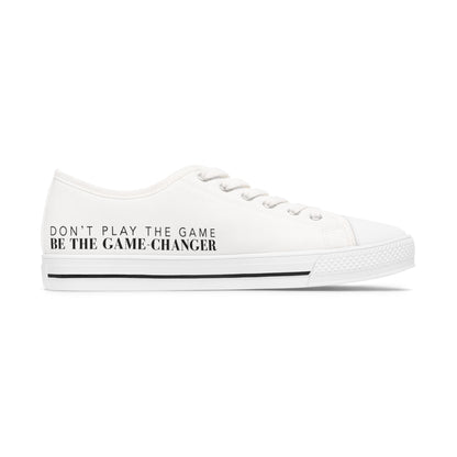 A side view of an all white women's converse style low top sneaker with don't play the game be the game changer written in black text across the side of the shoe with a black accent line in the leather trim