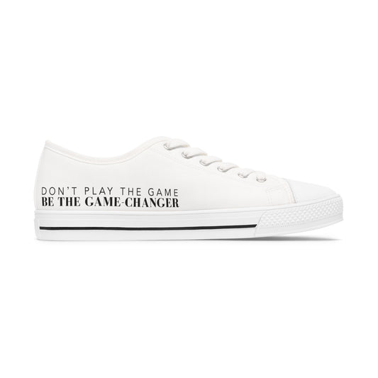 A side view of an all white women's converse style low top sneaker with don't play the game be the game changer written in black text across the side of the shoe with a black accent line in the leather trim