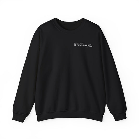 A cozy black crewneck sweater with white letters that say don't play the game be the game-changer over the left chest 