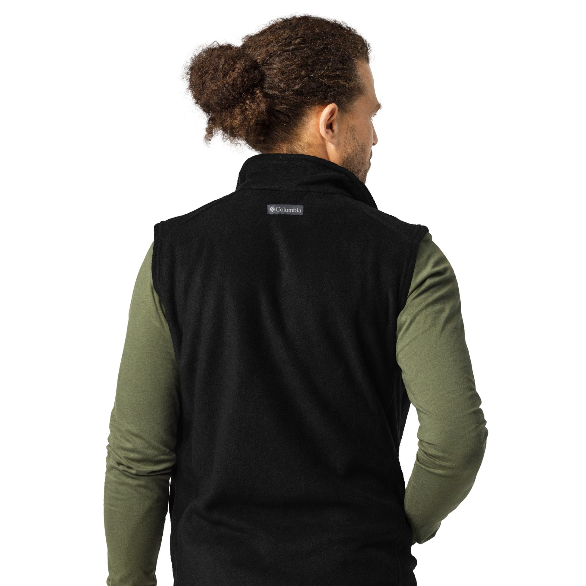 A man with brown curly hair pulled back into a bun wearing a long sleeve green shirt and a black Columbia fleece vest 